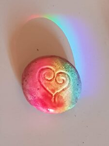 Cœur arc-en-ciel | Clémentine Rainbow Flow. Piece en céramique avec un coeur gravé et un arc en ciel de lumière visible colorant le coeur rose. Clémentine Degaine | Rainbow Flow: Art Hybride & Peinture Structurale Visionnaire